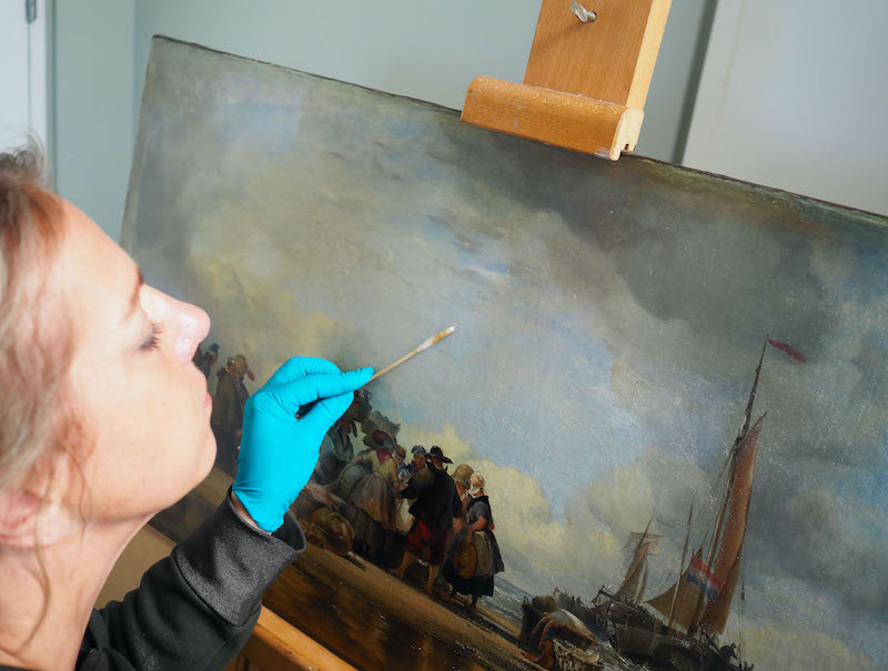 Sophie Reddington removing varnish from a painting